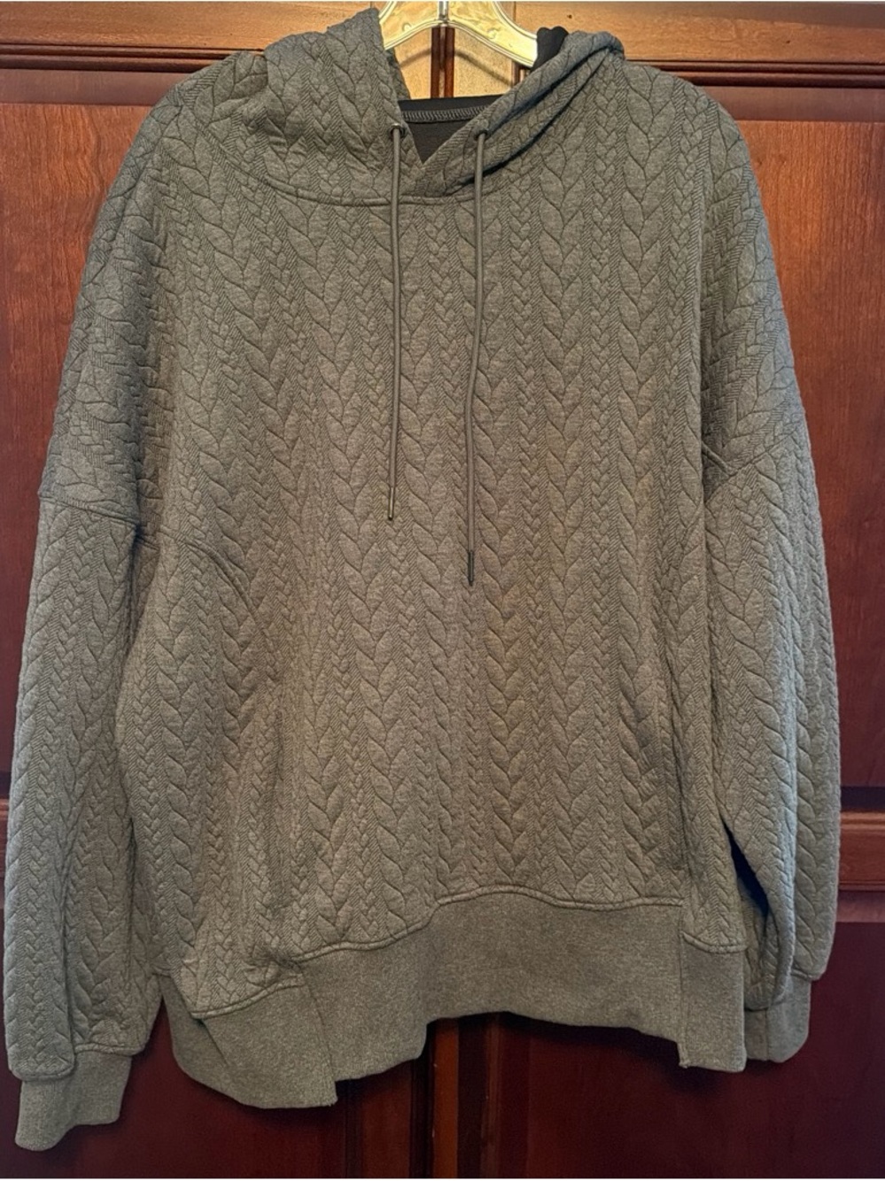 Women’s cable knit hoodie with front pockets.